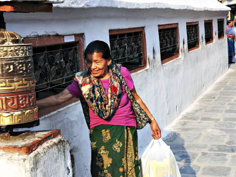 Frau dreht Gebetsmühle am Tempel