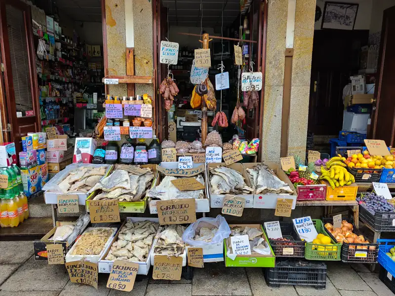 Marktstand mit verschiedenen Sorten getrocknetem Fisch wie Bacalhau, Graudo, Corronto und Cachacos, sowie Obst und Gemüse.