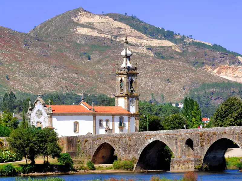 Historische Kirche und Steinbrücke in einer idyllischen Landschaft.