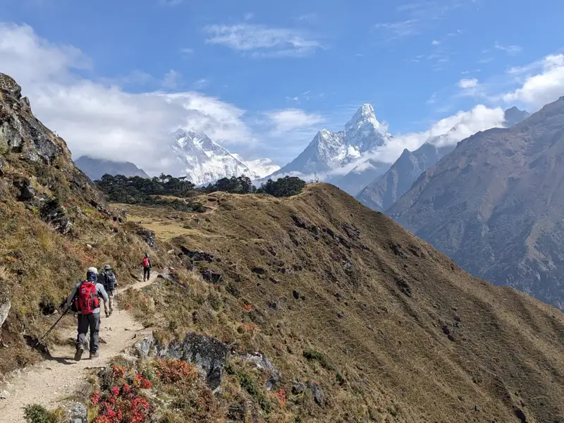 Wanderer auf einem Bergpfad mit Blick auf die schneebedeckten Gipfel des Himalayas.