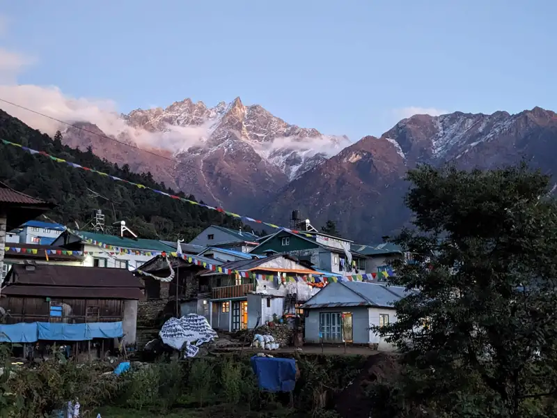 Bergdorf mit schneebedeckten Gipfeln im Hintergrund.