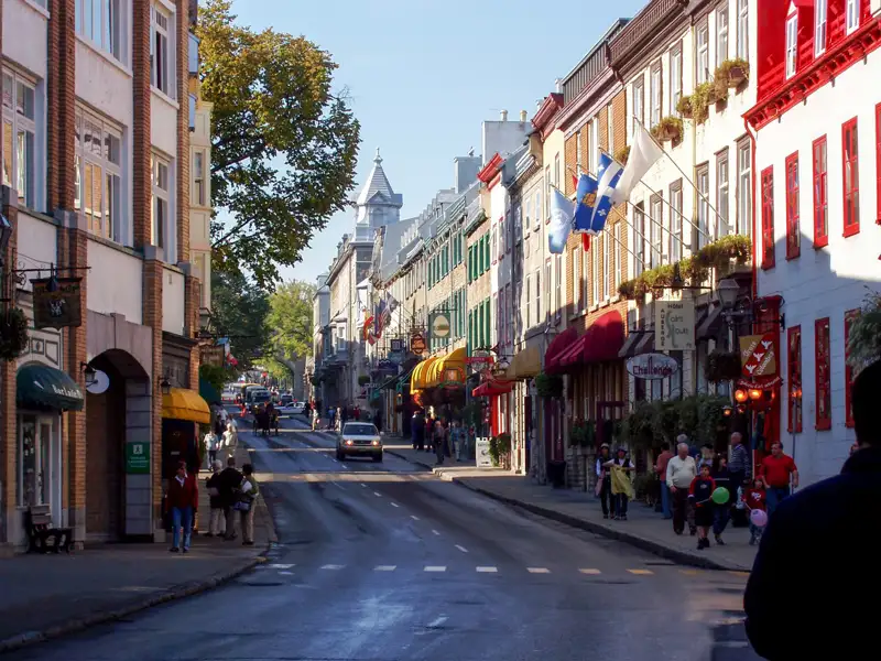 Eine Straße in Quebec City mit traditionellen Gebäuden und Fußgängern.