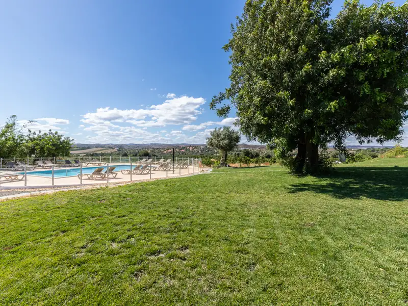 Pool mit Liegestühlen und Landschaftsblick.