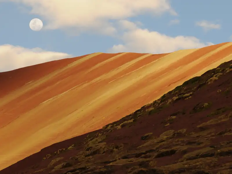 Farbiger Berghang mit sichtbarem Mond.