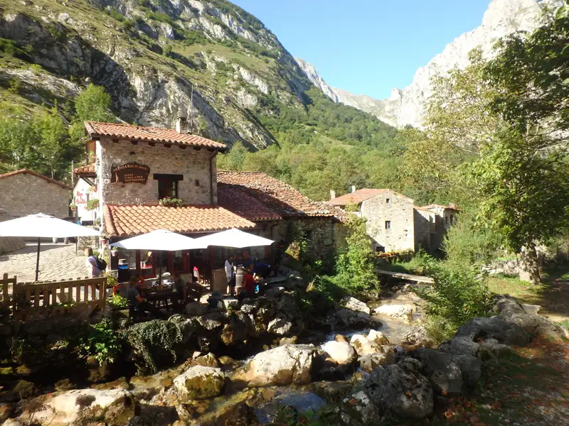 Restaurant in einem Bergdorf, umgeben von Bergen und einem Fluss.