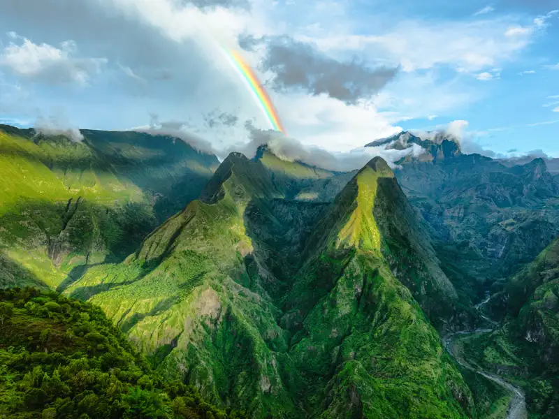 Panoramablick auf eine Bergkette mit einem Regenbogen.
