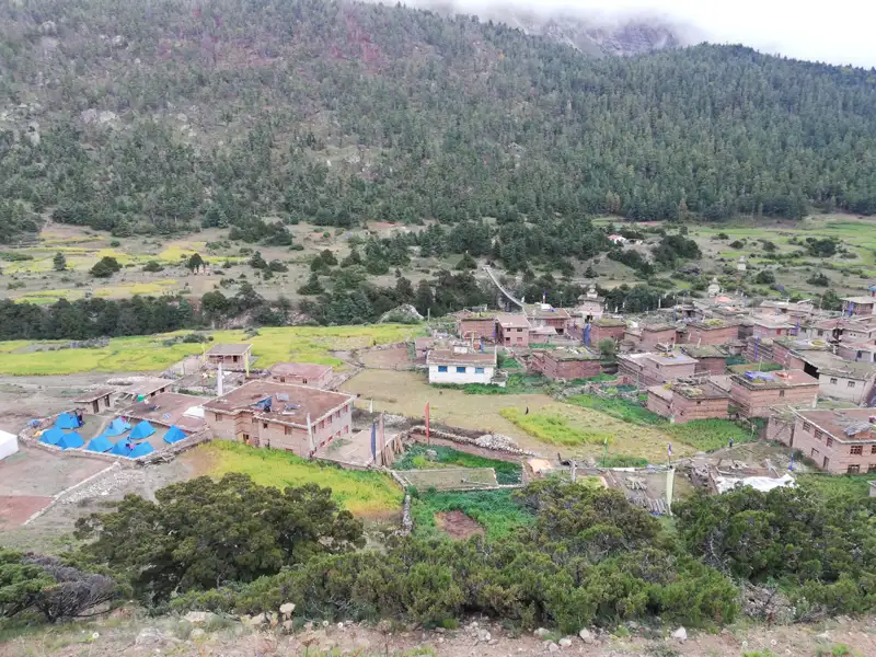 Dorf in einem Tal mit umliegenden Hügeln und Feldern.