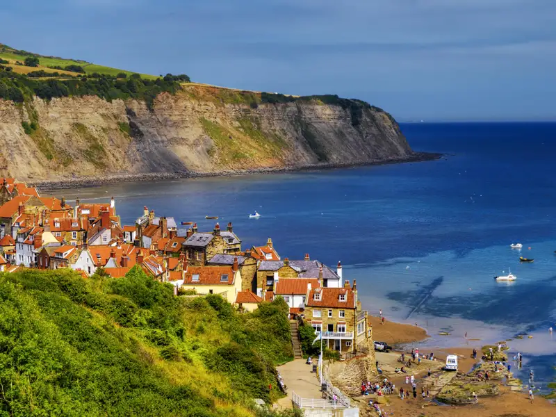 Idyllischer Küstenort mit roten Dächern und Blick auf das Meer.