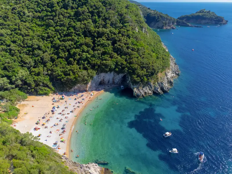 Luftansicht eines abgelegenen Strandes mit türkisfarbenem Wasser, weißem Sandstrand und bewaldeter Küste.
