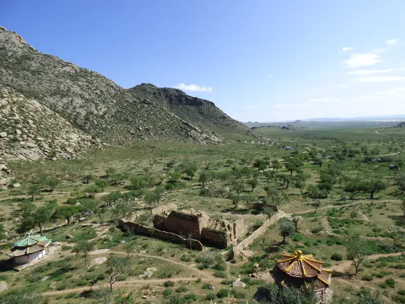 Ruinen und traditionelle Pavillons in einer Hügellandschaft.