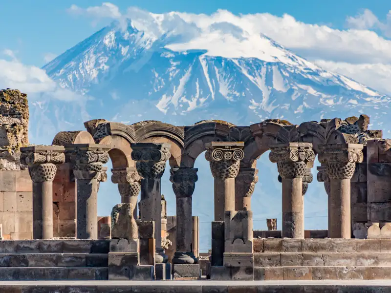 Blick auf die Säulen und Bögen der Ruinen von Zvartnots mit dem Berg Ararat im Hintergrund.