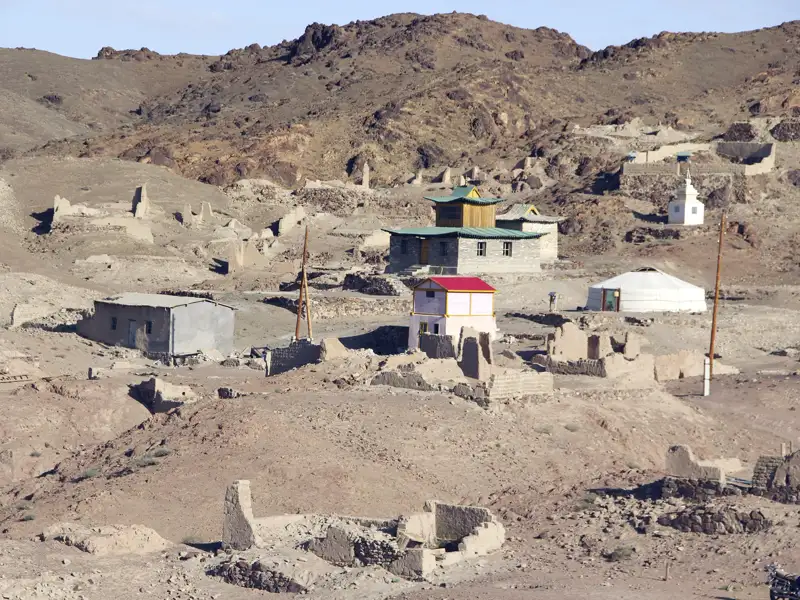 Gebäude und Ruinen in einer wüstenartigen Landschaft, möglicherweise Teil einer alten Siedlung.