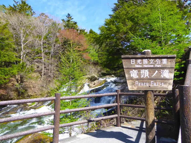 Ryuzu-Wasserfälle im Nikko-Nationalpark mit einem Schild, das den Namen des Wasserfalls und des Parks angibt.