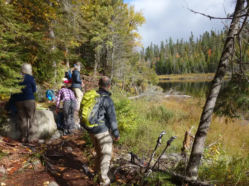Wandergruppe macht eine Pause während ihrer Wanderung am Ufer eines Sees.