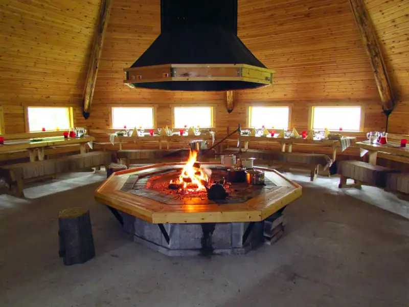 Lagerfeuer in einer Hütte mit gedeckten Tischen.