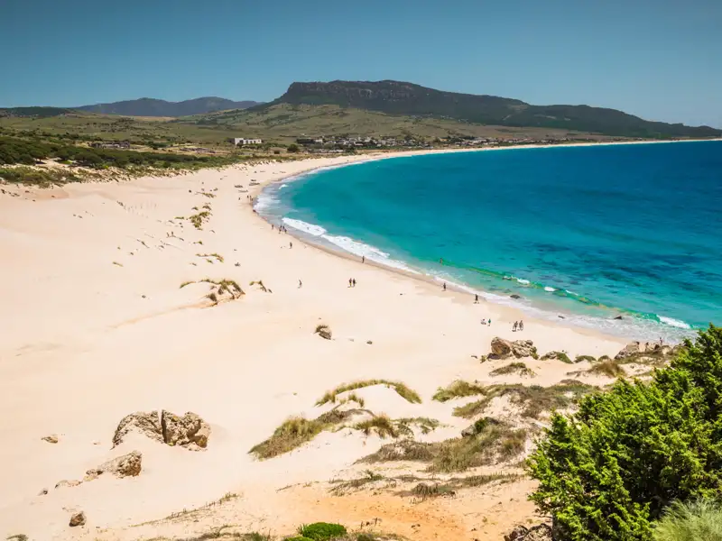 Panoramablick auf einen weißen Sandstrand und türkisfarbenes Meer.