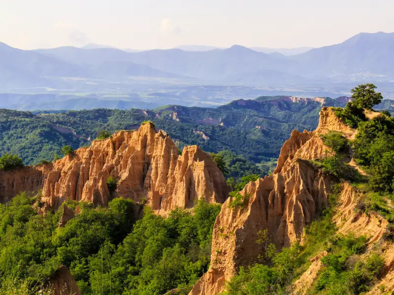Erodierte Sandsteinformationen in einer hügeligen Landschaft.
