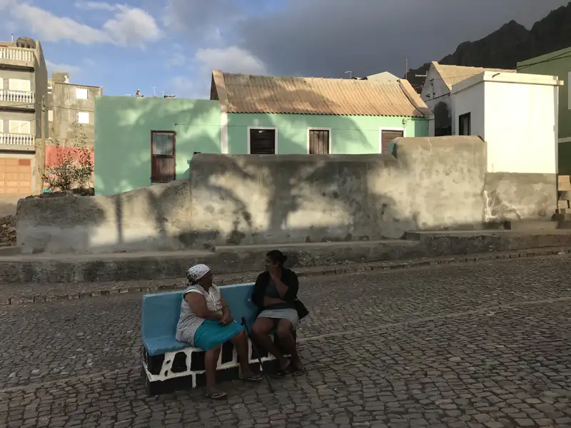 Zwei Frauen auf einer Bank in einer Ortschaft.