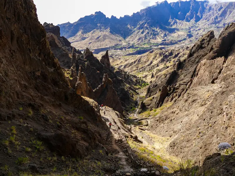 Wanderer auf einem Bergpfad in einer felsigen Schlucht.