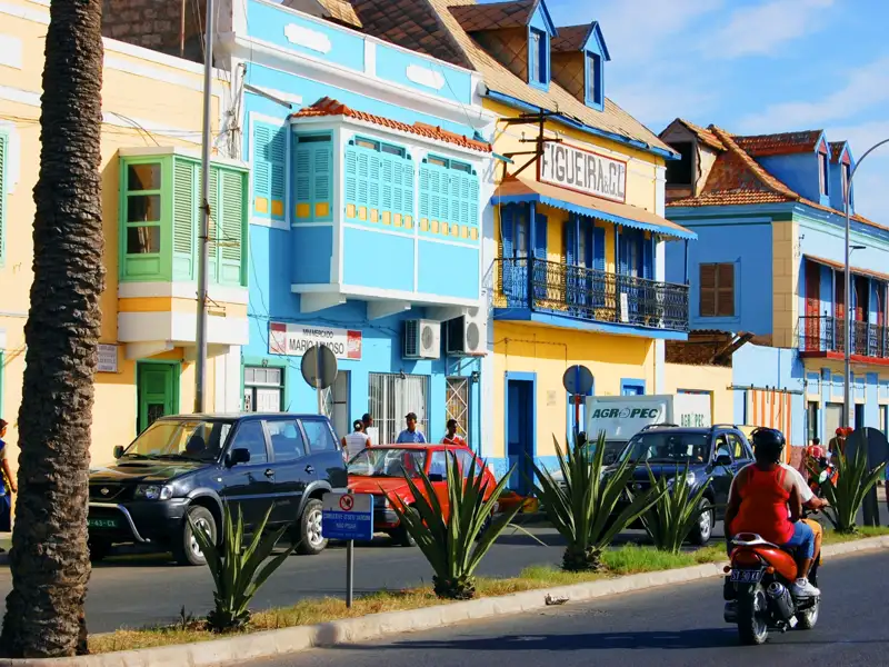 Straßenszene mit bunten Häusern und Verkehr.