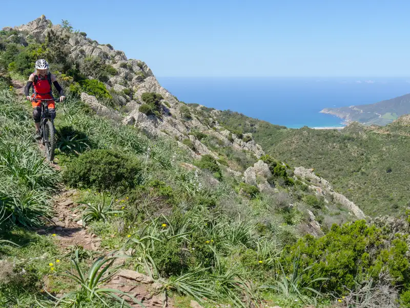 Mountainbiker auf einem Bergpfad mit Blick auf das Meer.