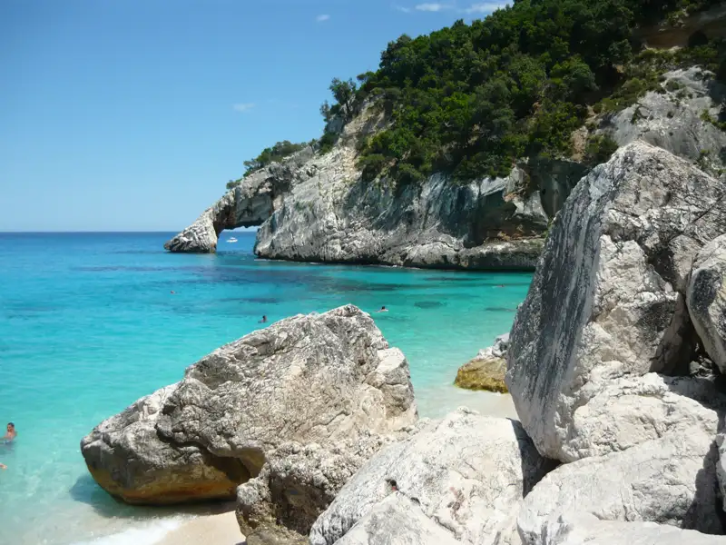 Türkisblaues Wasser und felsige Küste mit natürlichem Felsbogen.