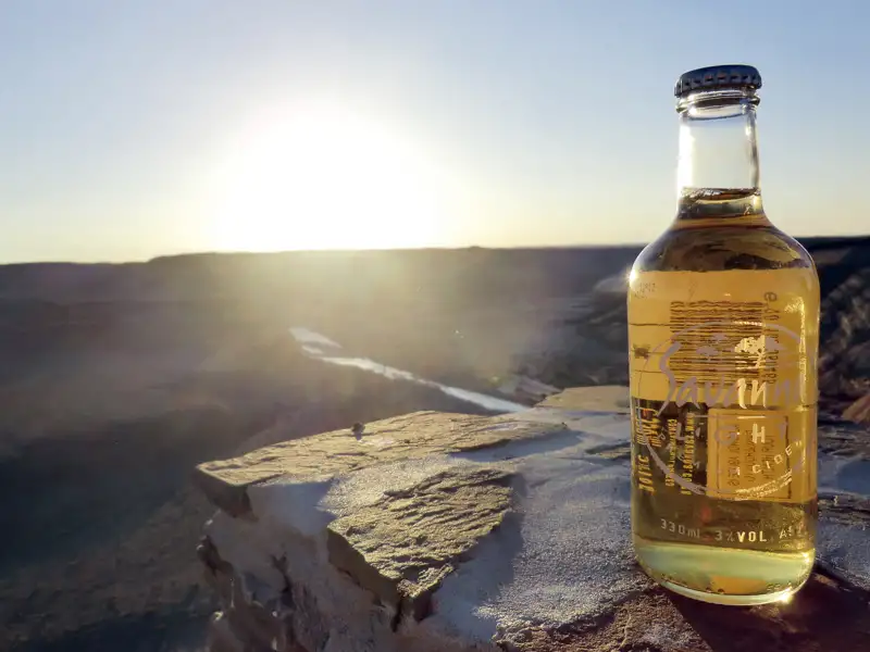 Eine Flasche Cider bei Sonnenuntergang über einer Schlucht.