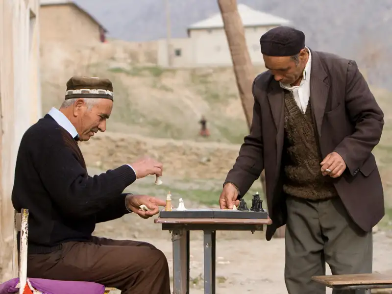 Zwei Männer spielen Schach an einem Tisch im Freien.