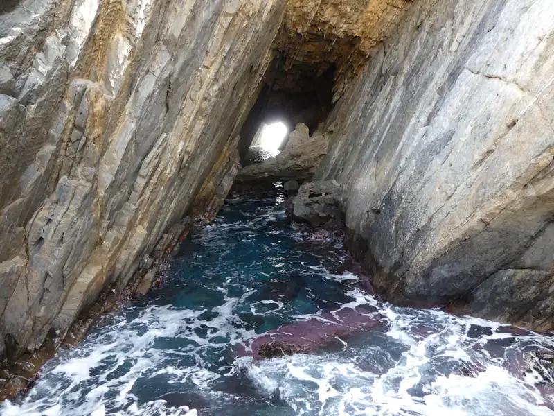 Meeresgrotte mit blauem Wasser und Felsformationen.