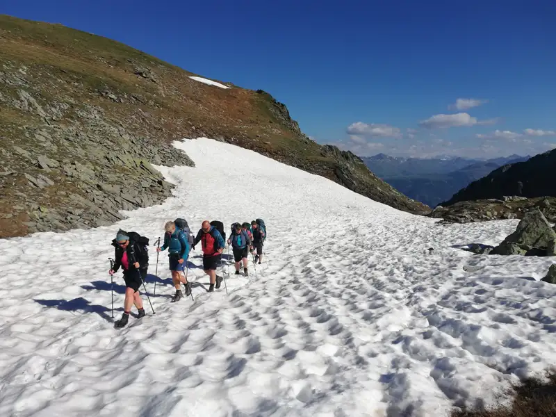 Wanderer überqueren ein Schneefeld in den Bergen.