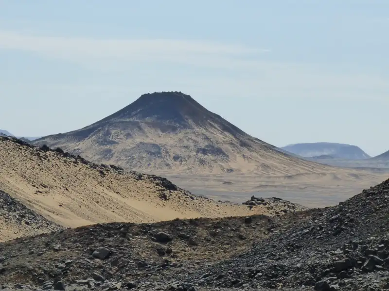 Kegelförmiger Berg in einer wüstenartigen Landschaft, aufgenommen während der Reise.