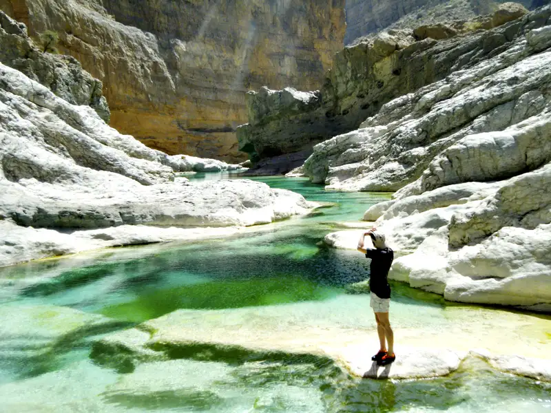 Eine Person betrachtet das türkisfarbene Wasser und die weißen Felsen der Schlucht.