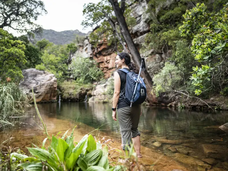 Wanderin genießt eine Pause am Ufer eines Bachs während ihrer Wanderung.