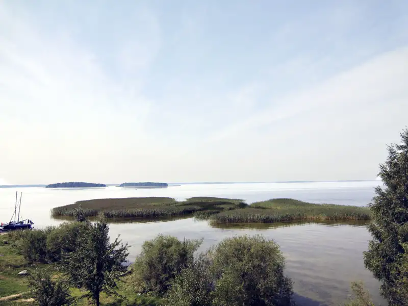 Schilfinseln im See mit Segelboot und Inseln im Hintergrund.