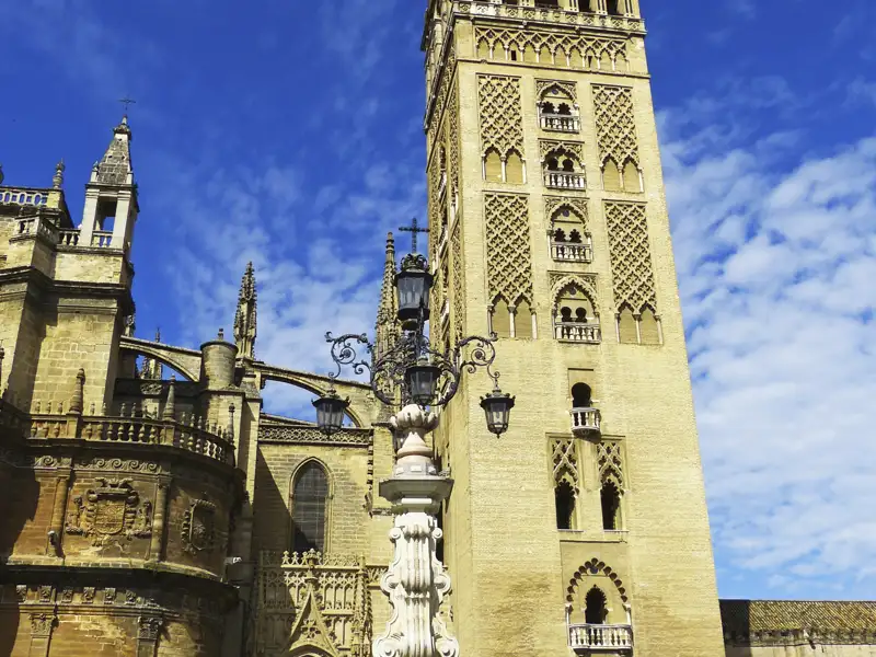 Die Giralda, der Glockenturm der Kathedrale von Sevilla, ragt vor einem blauen Himmel empor.