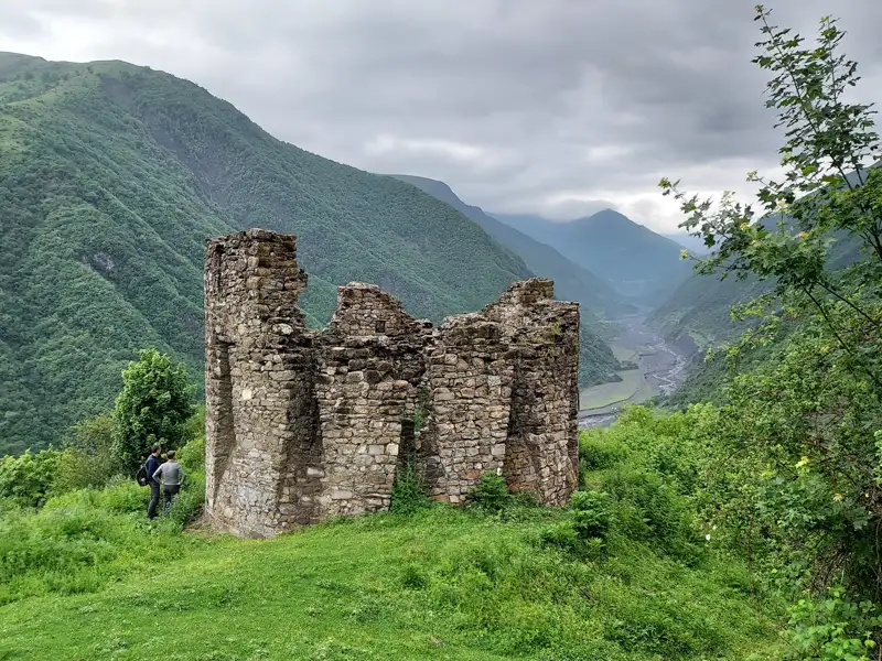 Alte Festungsruine mit Blick auf ein Tal in den Bergen.