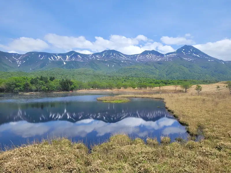 Stille Landschaft mit einem See, der die schneebedeckten Berge und den bewaldeten Uferbereich spiegelt.