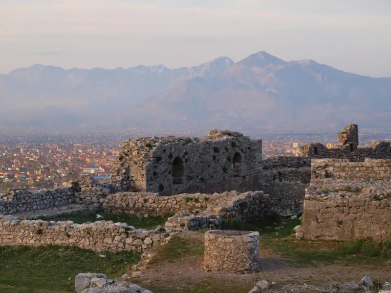Blick von einer Burgruine auf die Stadt und die Berge.