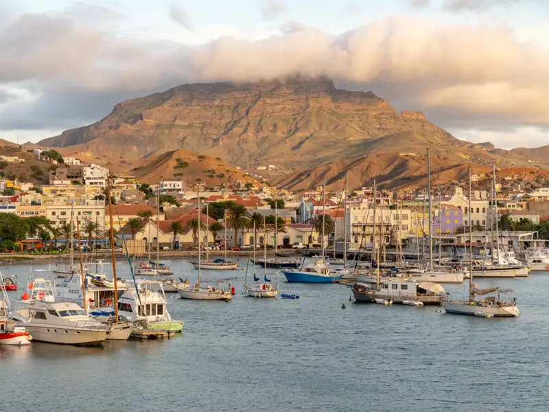 Hafenstadt mit vielen Booten und einem Berg im Hintergrund.