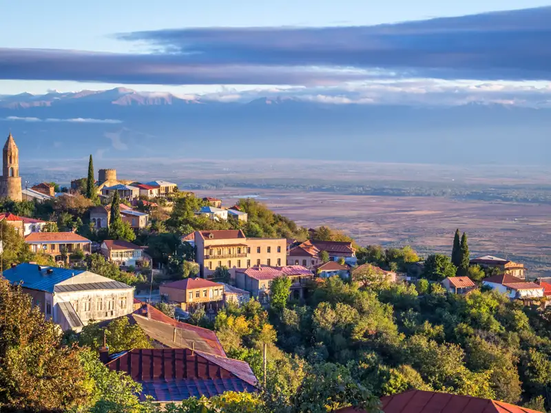 Panorama einer georgischen Stadt mit traditioneller Architektur und Bergkulisse.