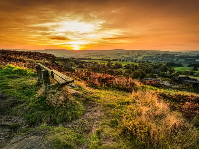 Ruheplatz mit Bank und Ausblick auf die Landschaft bei Sonnenuntergang.