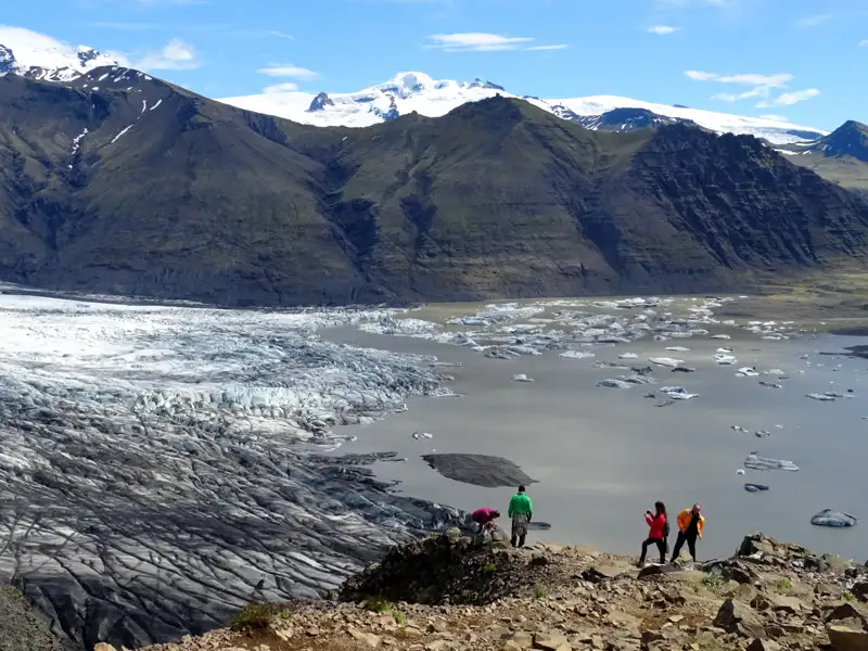 Touristen beobachten einen Gletscher und einen Gletschersee.