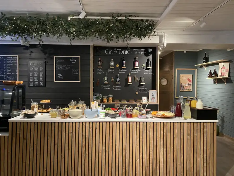 Frühstücksbuffet mit verschiedenen Speisen und Getränken, darunter Kaffee, Saft und Gin Tonic.