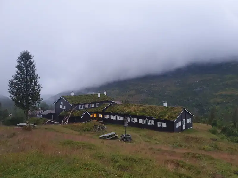 Begrünte Berghütte in den Bergen im Nebel.