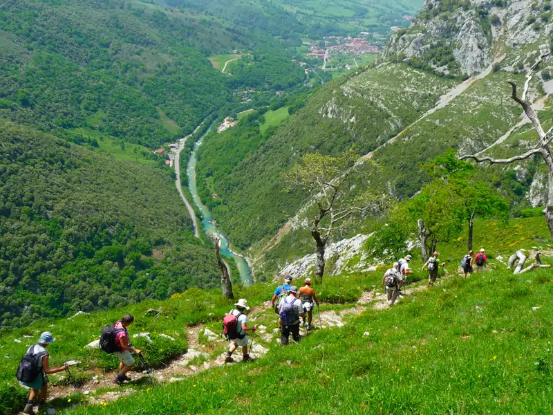 Wandergruppe auf einem Bergpfad mit Blick auf das Flusstal und die umliegende Landschaft.