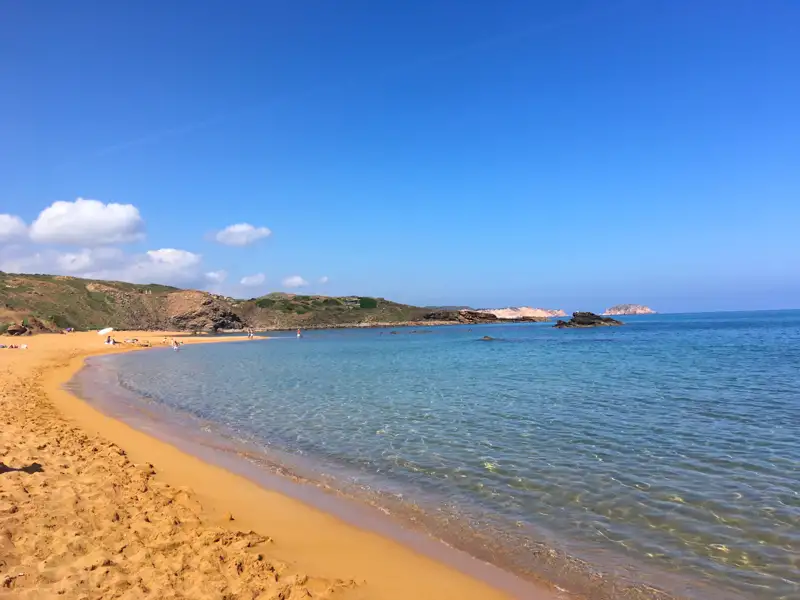 Goldener Sandstrand und türkisblaues Wasser einer malerischen Bucht.