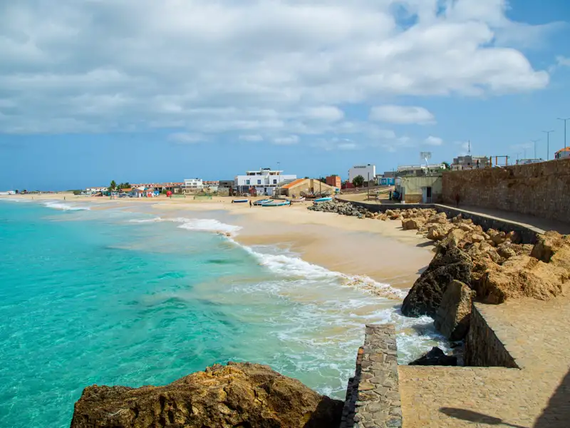 Küstenlandschaft mit türkisfarbenem Wasser und Sandstrand.