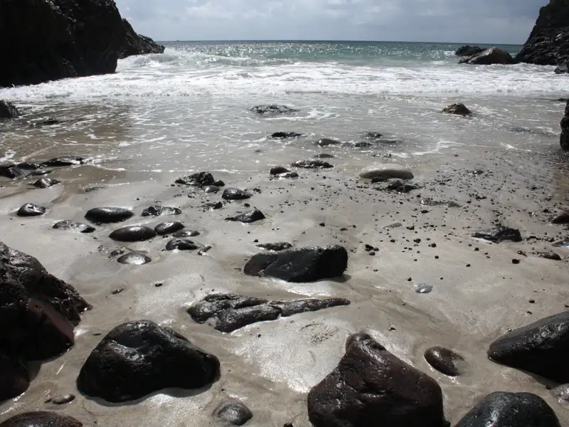 Strand mit Steinen und Wellen