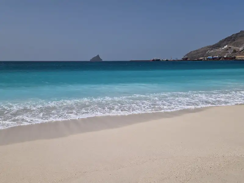 Türkisblaues Wasser und weißer Sandstrand an einem Reiseziel.