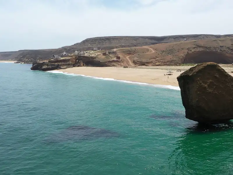Strand mit Felsen und türkisfarbenem Wasser.